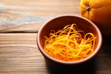 Photo of Orange zest and fresh fruit on wooden table, closeup. Space for text