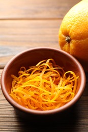 Photo of Orange zest and fresh fruit on wooden table, closeup