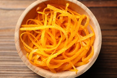 Photo of Fresh orange zest in bowl on wooden table, top view