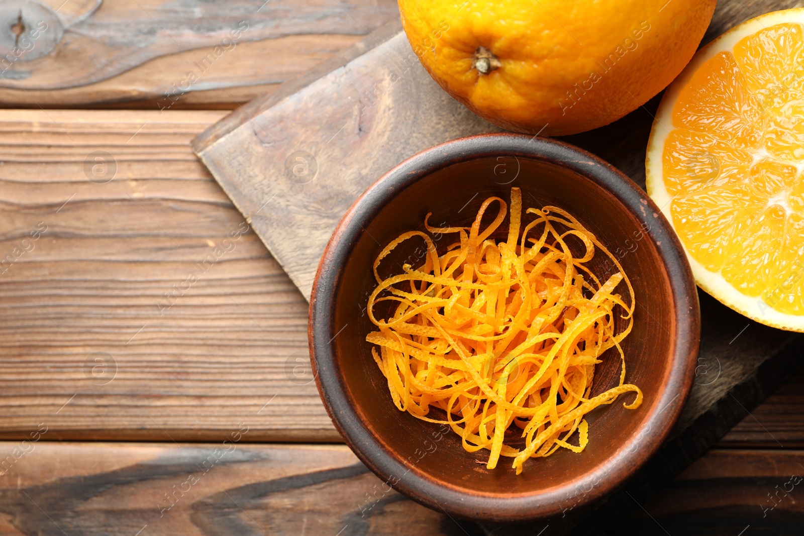 Photo of Orange zest and fresh fruits on wooden table, top view. Space for text