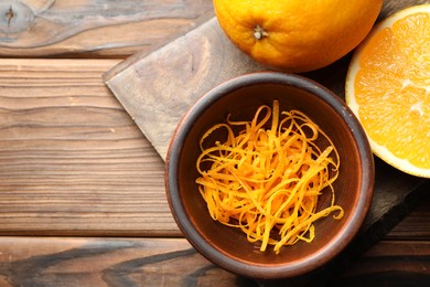 Photo of Orange zest and fresh fruits on wooden table, top view. Space for text