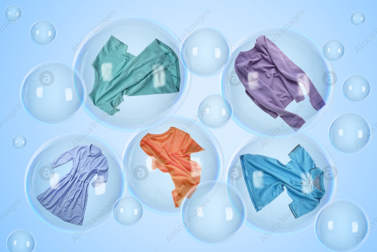 Image of Several soap bubbles with clothes inside and empty ones floating on light blue background. Laundry day