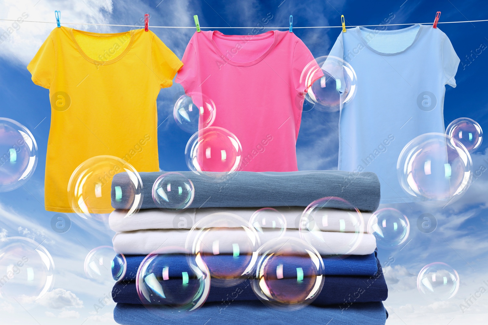 Image of Stacked laundry and hanging on clothes rope apparel among floating soap bubbles against sky