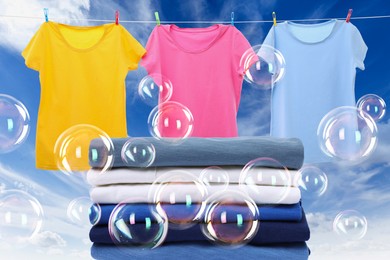 Image of Stacked laundry and hanging on clothes rope apparel among floating soap bubbles against sky