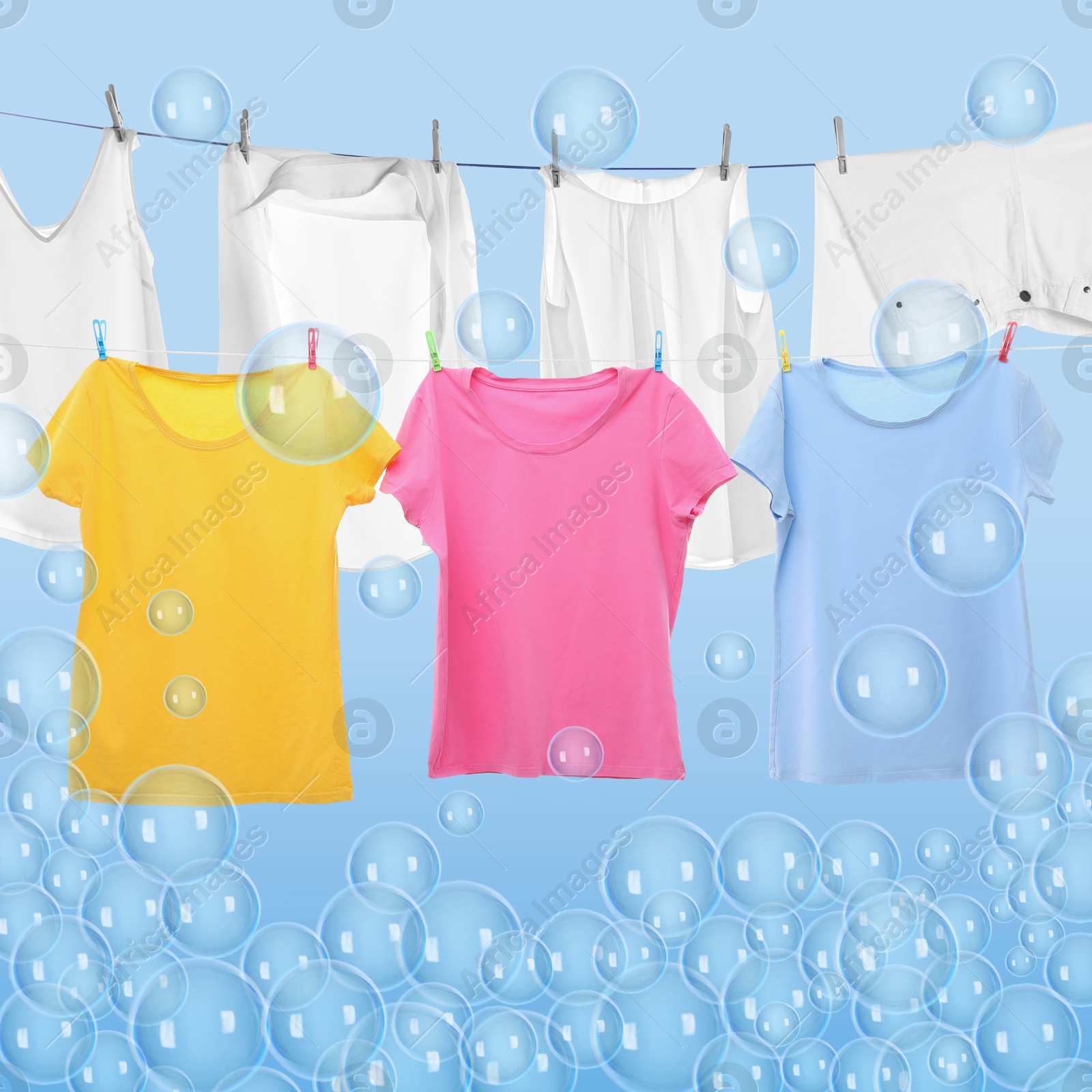 Image of Laundry hanging on clothes rope among floating soap bubbles on light blue background