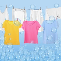 Image of Laundry hanging on clothes rope among floating soap bubbles on light blue background