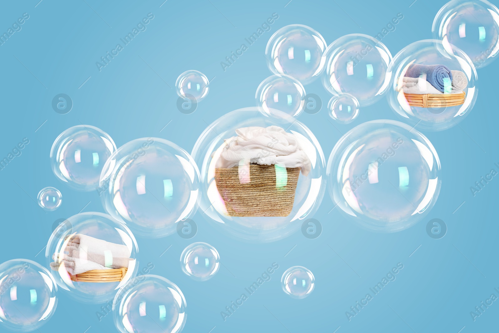 Image of Several soap bubbles with laundry inside and empty ones floating on light blue background