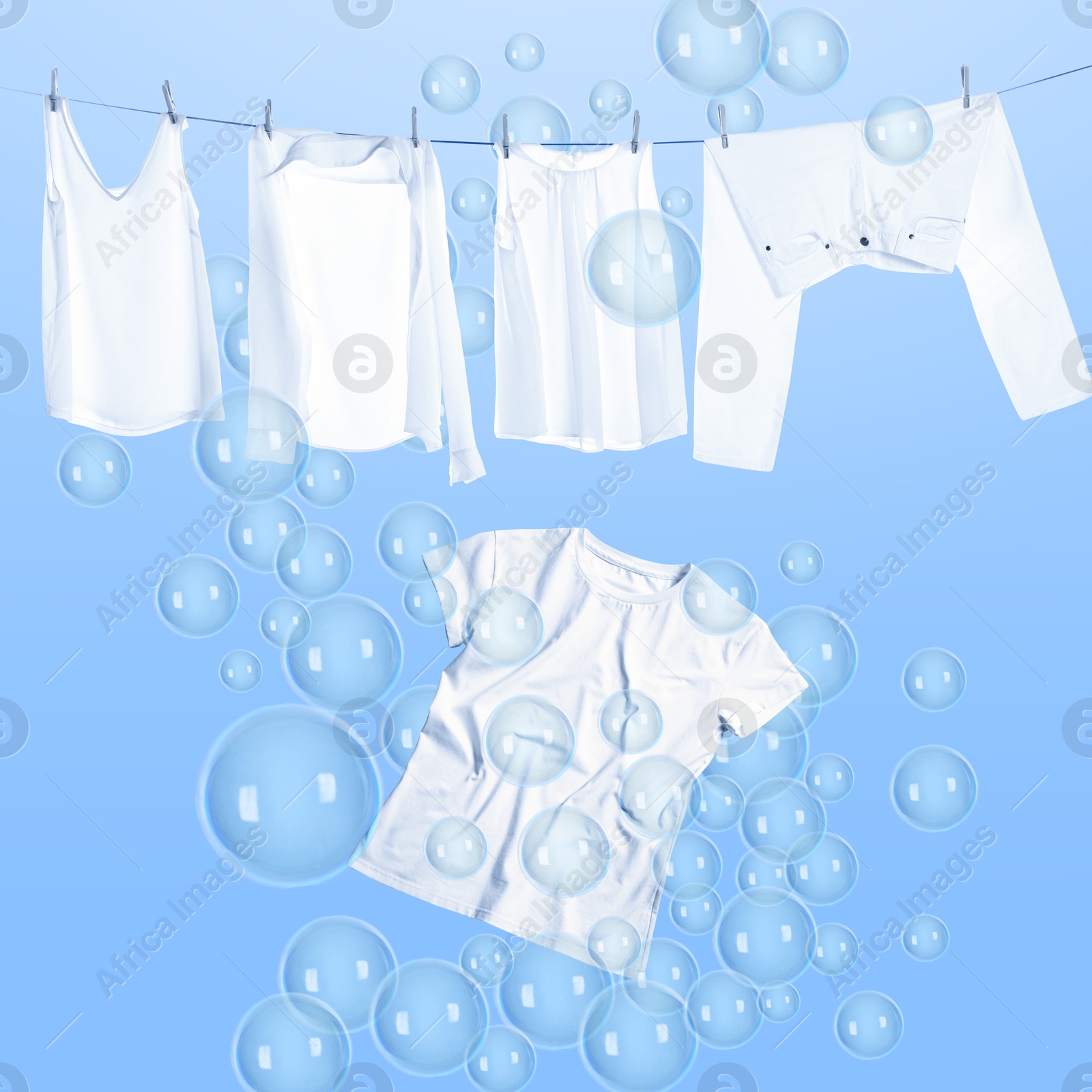 Image of Laundry hanging on clothes rope and flying t-shirt among floating soap bubbles on light blue background