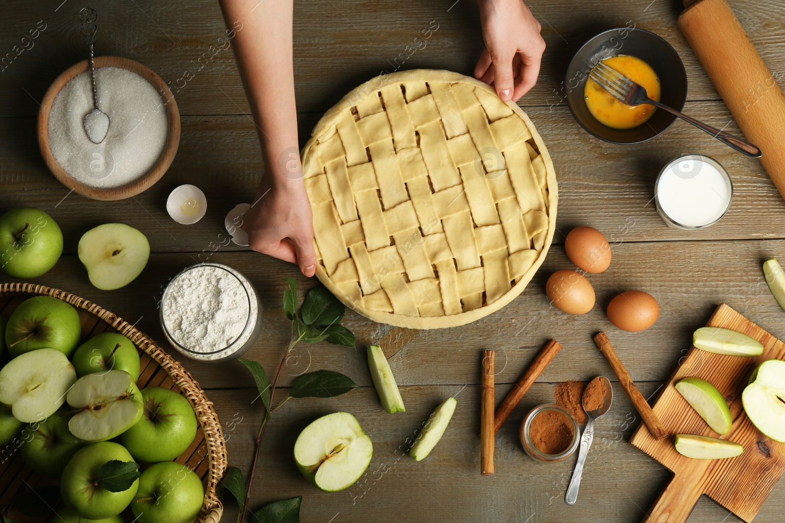 Photo of Woman making homemade apple pie and ingredients on wooden table, top view