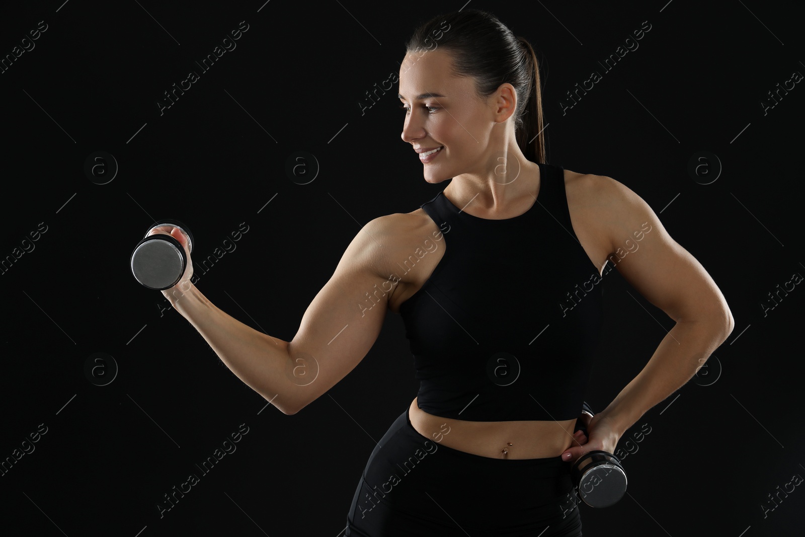 Photo of Woman exercising with dumbbells on black background