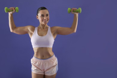 Photo of Woman exercising with dumbbells on purple background, space for text