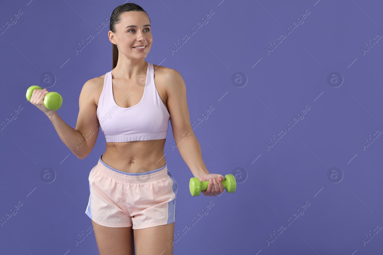 Photo of Woman exercising with dumbbells on purple background, space for text