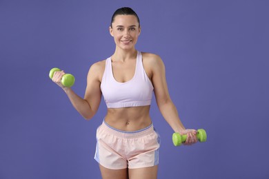 Photo of Woman exercising with dumbbells on purple background