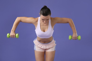 Photo of Woman exercising with dumbbells on purple background