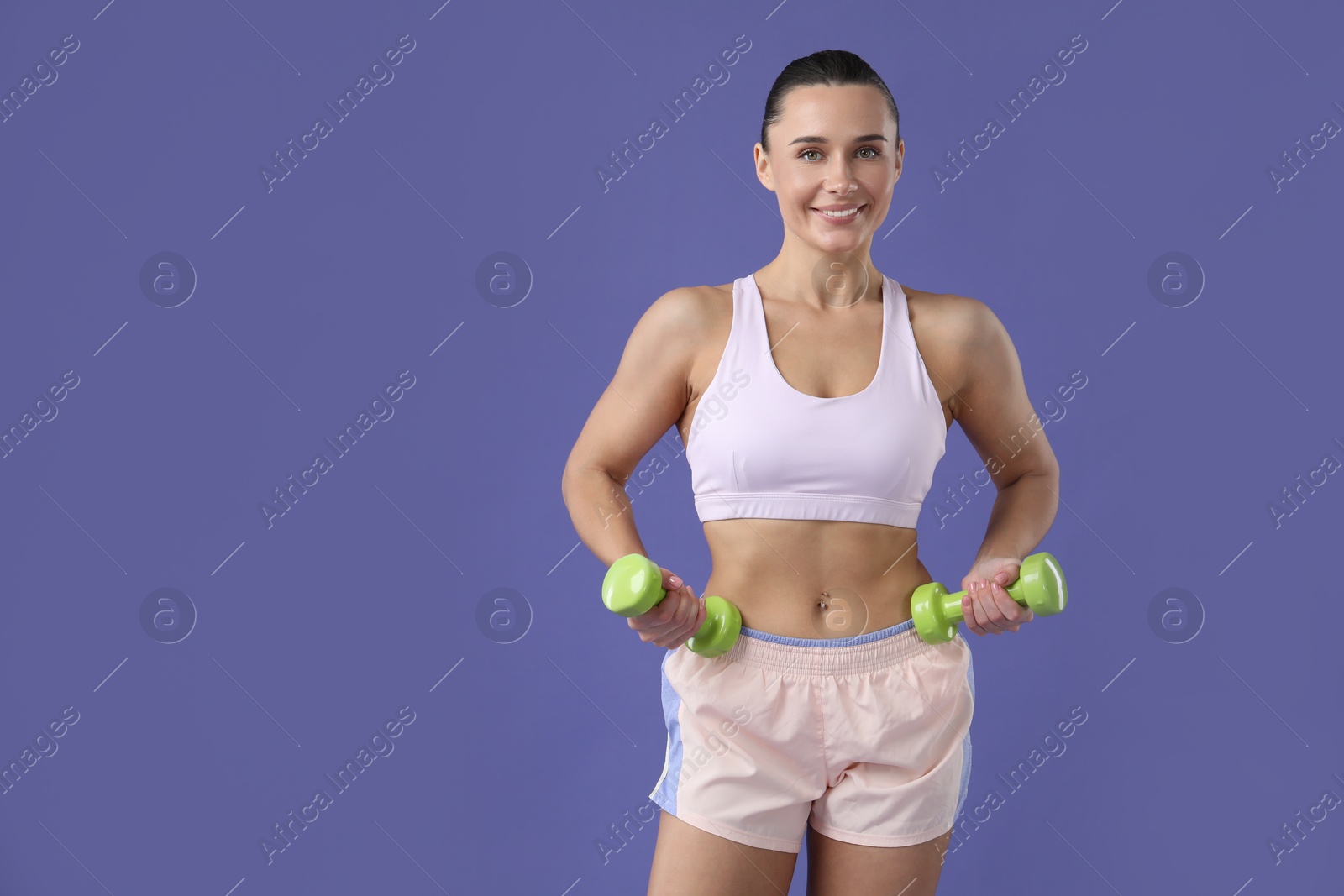 Photo of Woman exercising with dumbbells on purple background, space for text