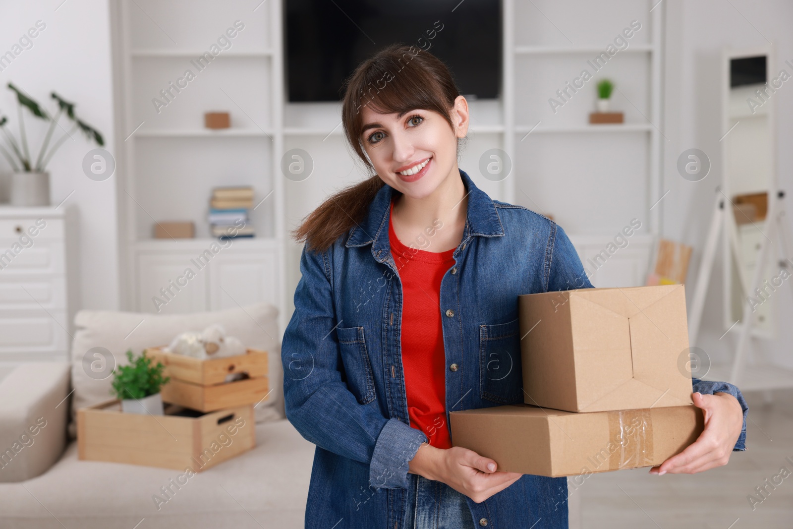 Photo of Happy woman with moving boxes in new apartment. Housewarming party