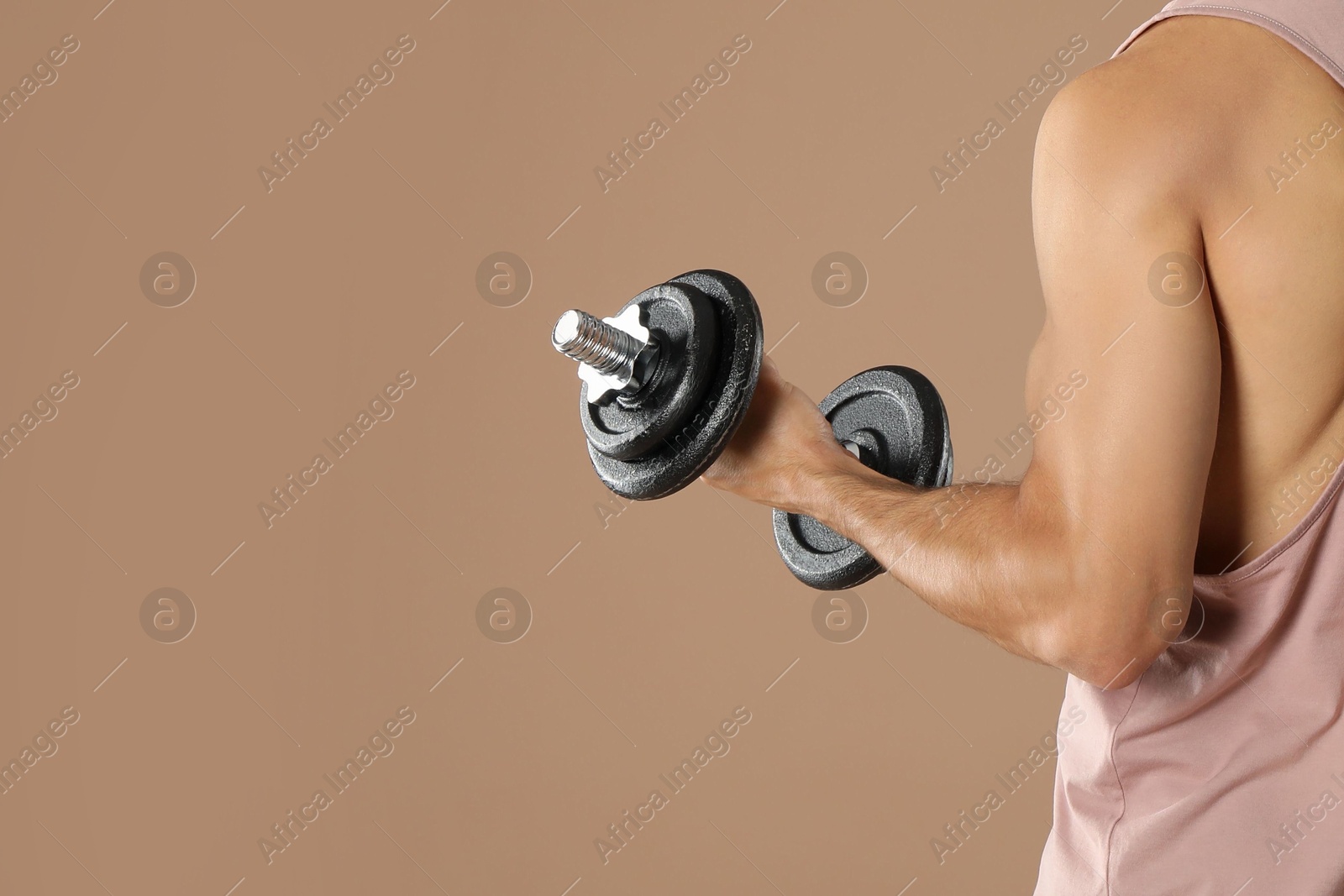 Photo of Man exercising with barbell on light brown background, closeup. Space for text