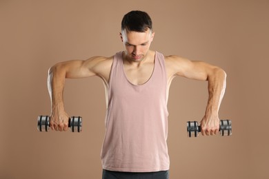 Man exercising with dumbbells on light brown background