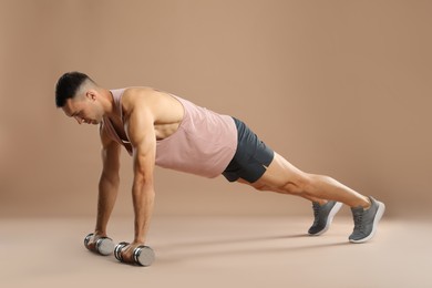 Photo of Man exercising with dumbbells on light brown background