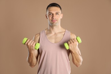 Photo of Man exercising with dumbbells on light brown background