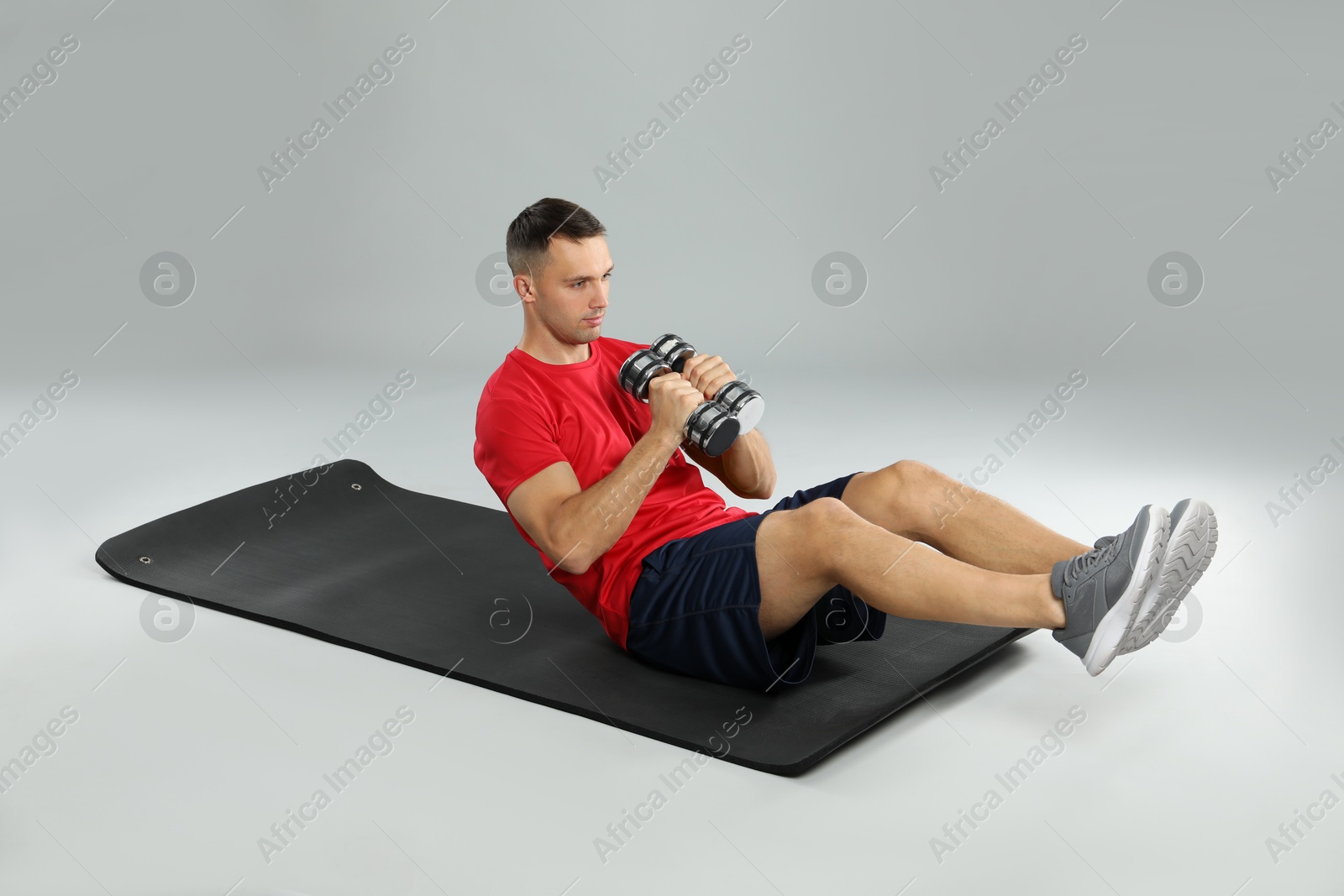 Photo of Man exercising with dumbbells on grey background