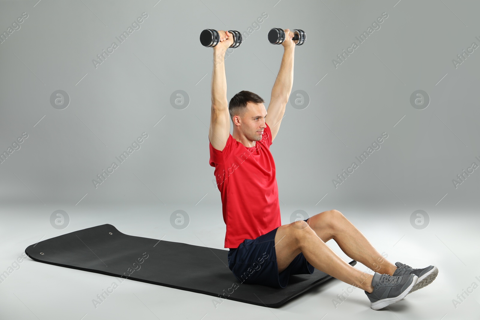 Photo of Man exercising with dumbbells on grey background