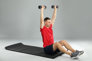 Photo of Man exercising with dumbbells on grey background