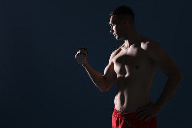 Photo of Man exercising with dumbbell on dark blue background, space for text