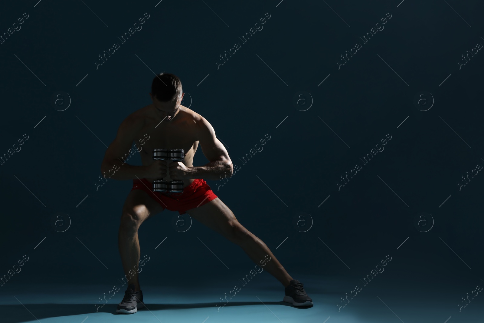 Photo of Man exercising with dumbbells on dark blue background, space for text