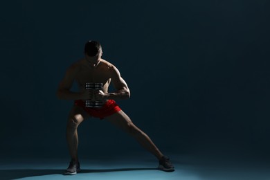 Photo of Man exercising with dumbbells on dark blue background, space for text