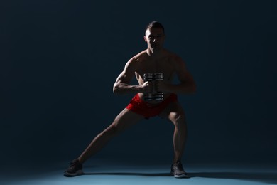 Photo of Man exercising with dumbbells on dark blue background