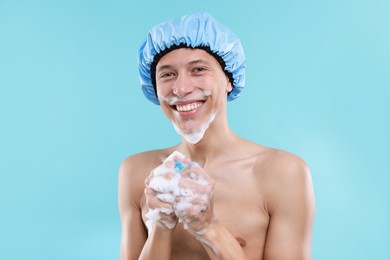 Photo of Man with shower cap and mesh sponge on light blue background