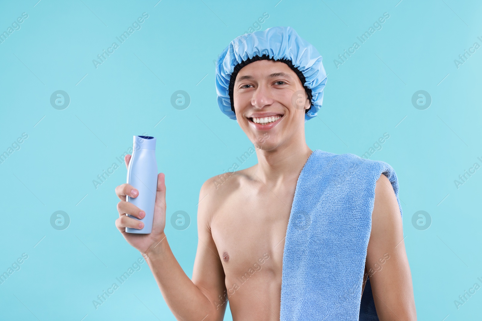 Photo of Man with shower cap, shampoo and towel on light blue background