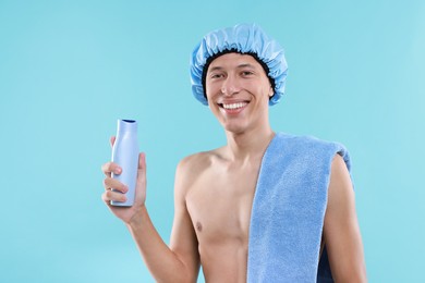 Photo of Man with shower cap, shampoo and towel on light blue background