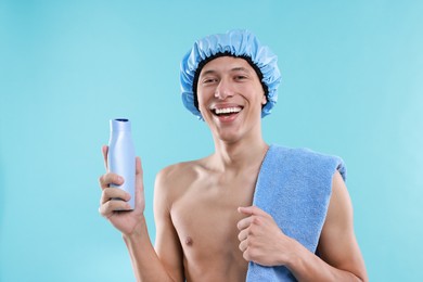 Photo of Man with shower cap, shampoo and towel on light blue background