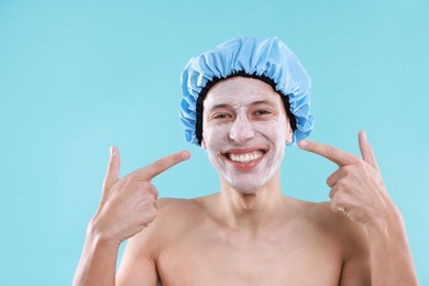 Photo of Man in shower cap with cream on his face against light blue background