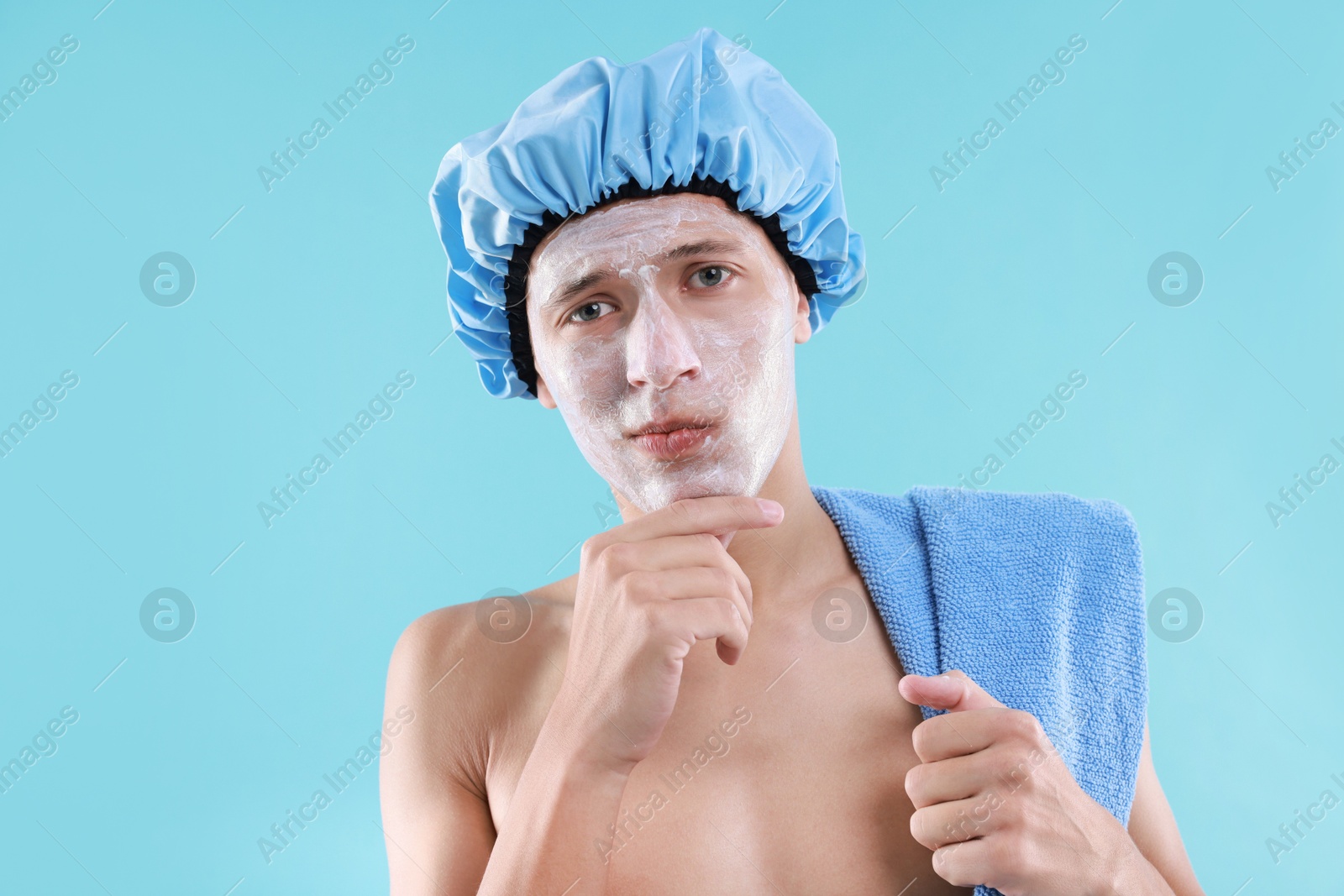 Photo of Man in shower cap with cream on his face against light blue background