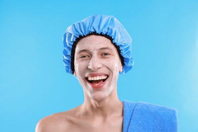 Photo of Man in shower cap with cream on his face against light blue background