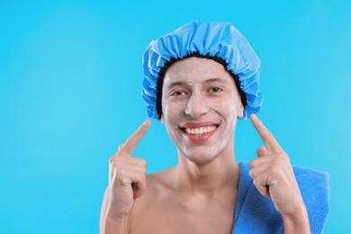 Photo of Man in shower cap with cream on his face against light blue background