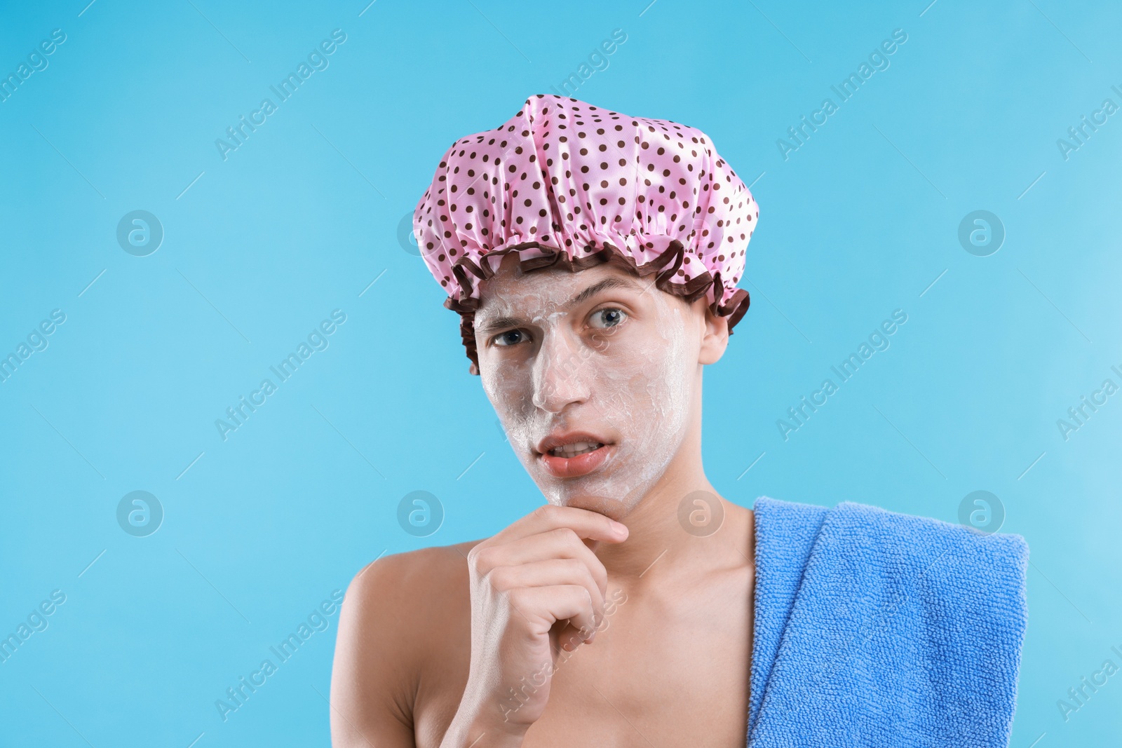 Photo of Man in shower cap with cream on his face against light blue background