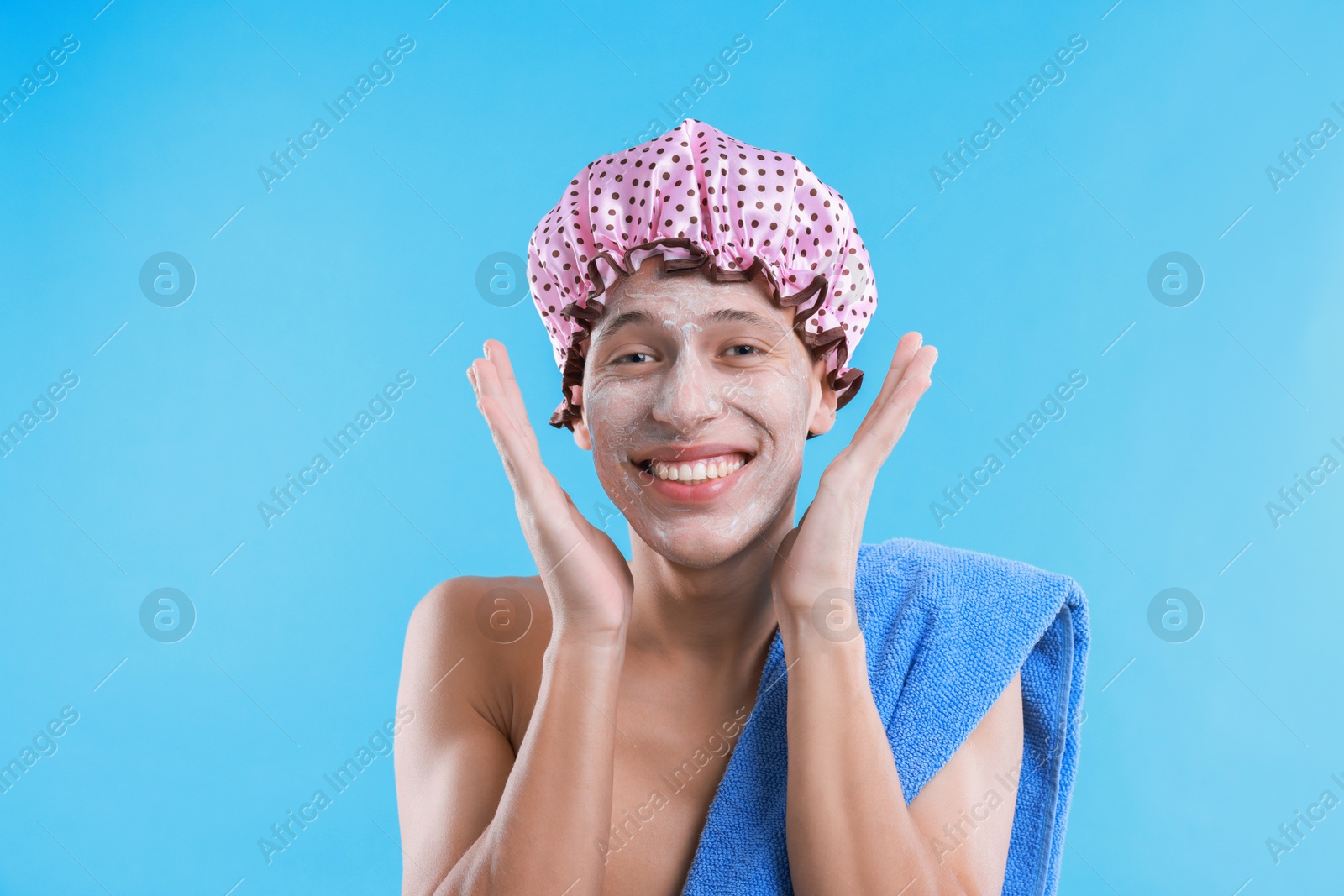 Photo of Man in shower cap with cream on his face against light blue background