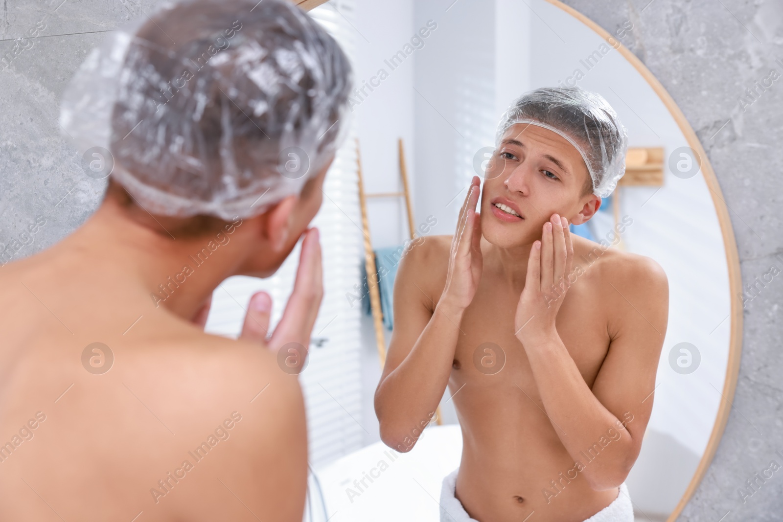 Photo of Man wearing shower cap near mirror in bathroom