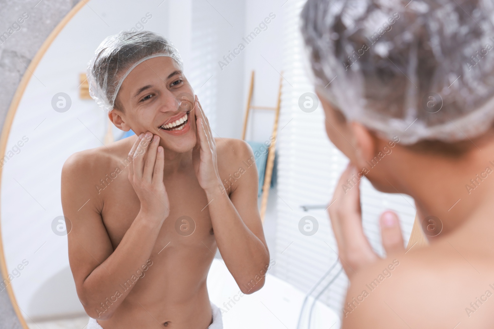 Photo of Man wearing shower cap near mirror in bathroom