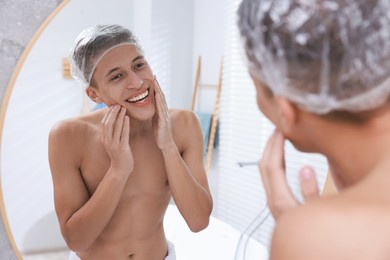 Photo of Man wearing shower cap near mirror in bathroom