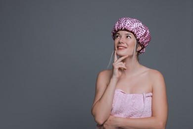 Photo of Happy woman in shower cap on grey background, space for text