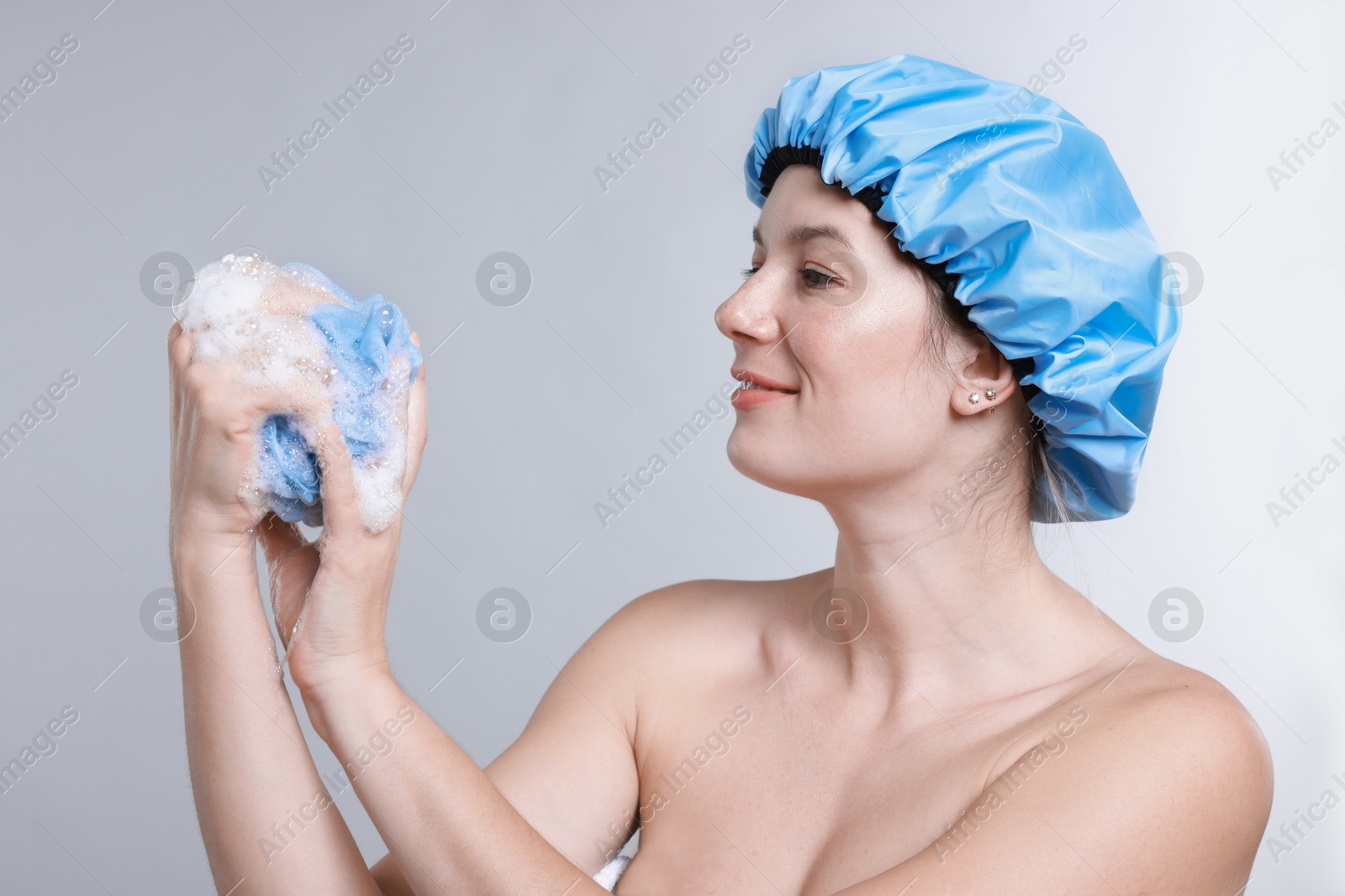 Photo of Woman with shower cap and mesh sponge on grey background