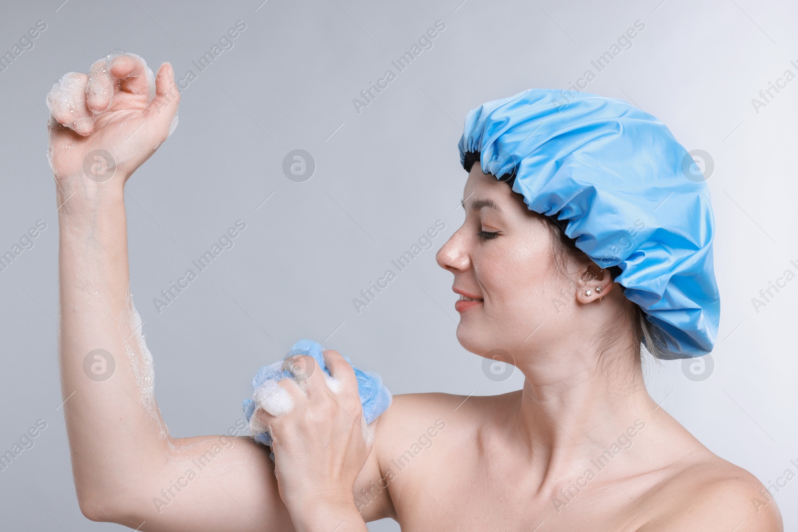 Photo of Woman with shower cap and mesh sponge on grey background