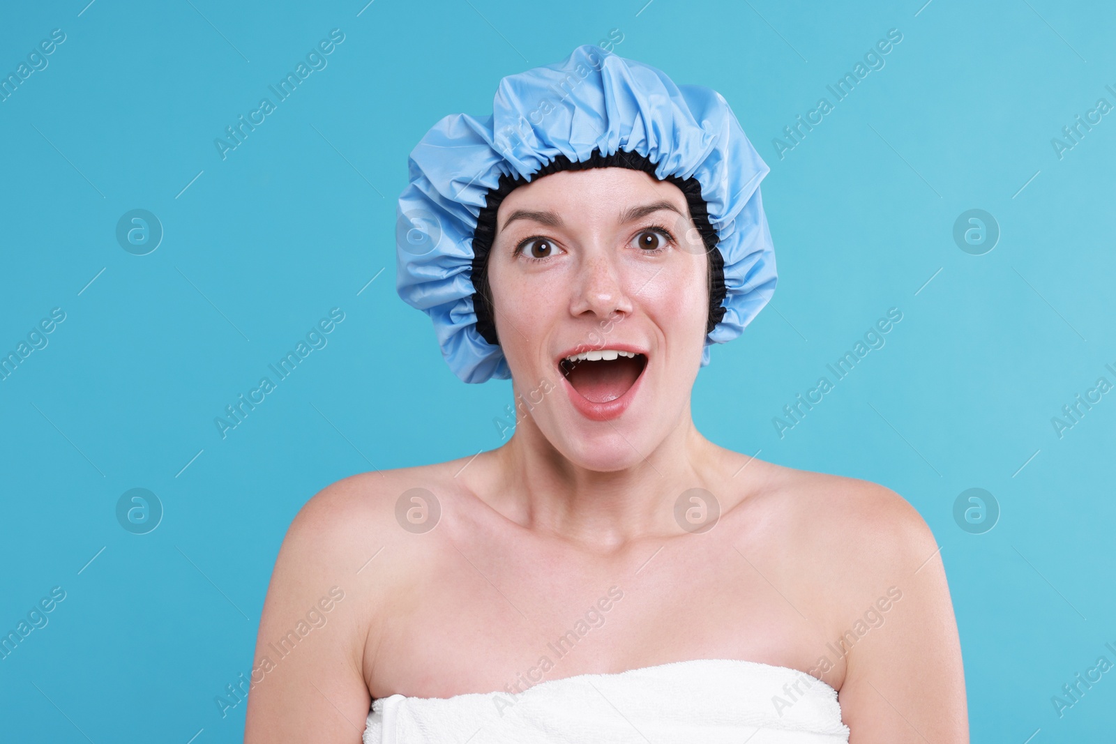 Photo of Emotional woman in shower cap on light blue background