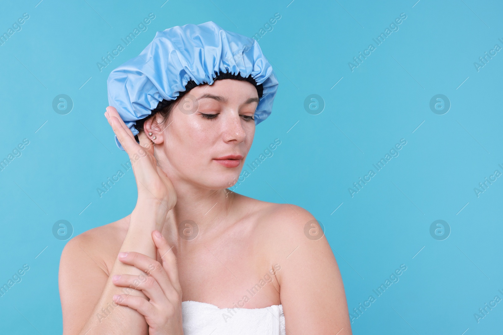 Photo of Woman wearing shower cap on light blue background