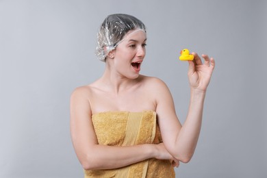 Photo of Woman with shower cap and bath duck on grey background